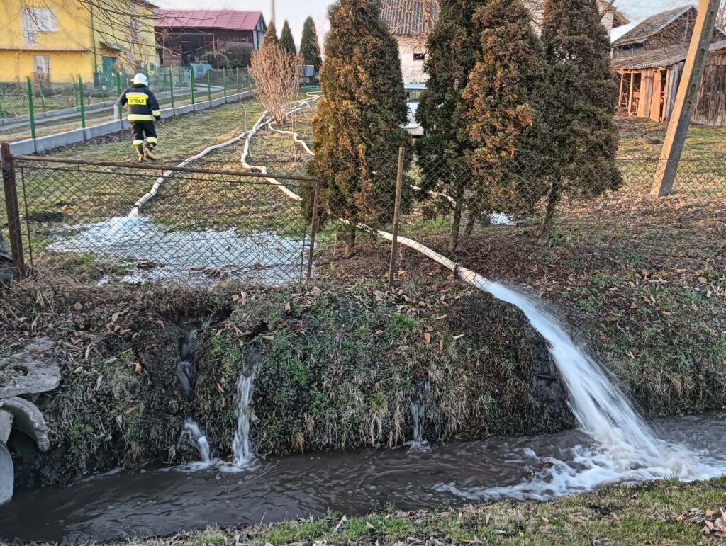 Strażacy podczas działań związanych z pompowaniem wody z zalanej posesji w miejscowości Łapajówka