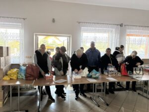 Mieszkańcy odbierający paczki żywnościowe w Wiejskim Domu Kultury w Tryńczy podczas akcji pomocowej