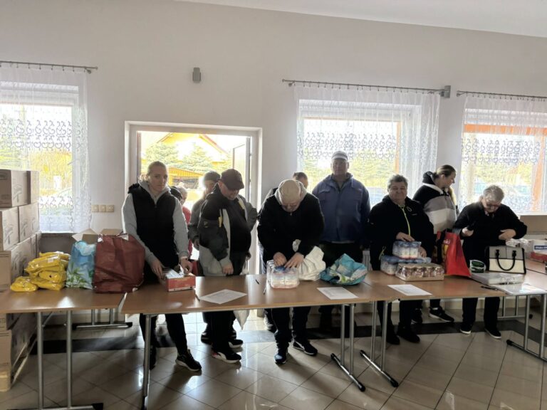 Mieszkańcy odbierający paczki żywnościowe w Wiejskim Domu Kultury w Tryńczy podczas akcji pomocowej
